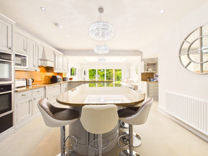 Modern kitchen-diner with white cabinetry, island seating, pendant lights and garden views