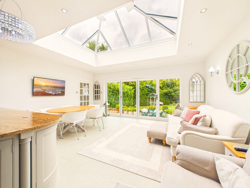 Bright open-plan living space with skylight, kitchen island, seating area, and garden views through patio doors