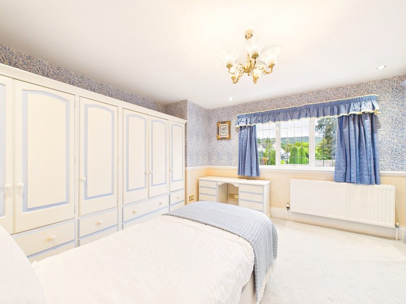 Bright bedroom with double bed, cream wardrobe, blue curtains and window