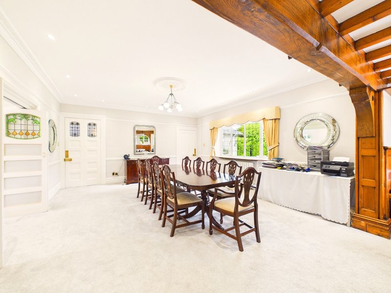 Spacious dining room with wooden table, chairs, exposed beams and kitchen area