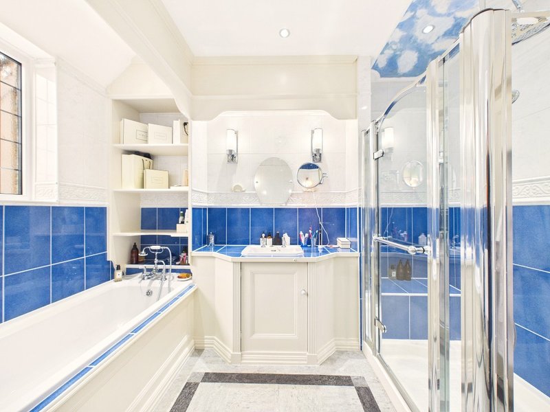 Modern bathroom with blue tile walls, white vanity, bathtub and shower enclosure