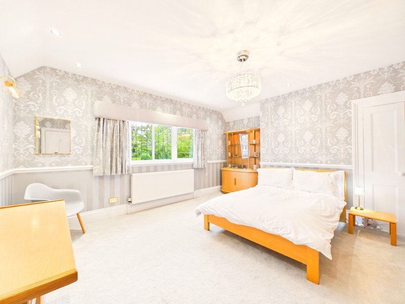 Bright bedroom with double bed, wooden furniture, patterned wallpaper and garden view