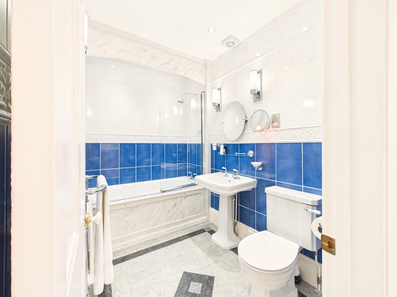 Bathroom with blue tile walls, white bath, pedestal sink and toilet
