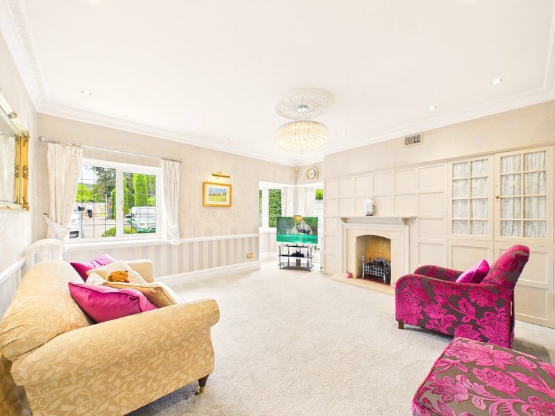 Spacious living room with cream and pink furnishings, fireplace, large windows and built-in shelving