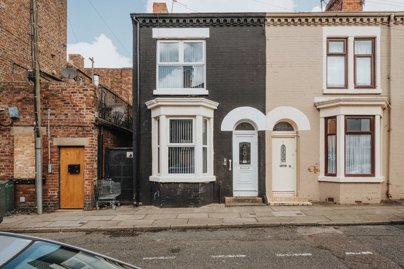 Street view of Victorian terraced houses with black and cream facades and arched doorways