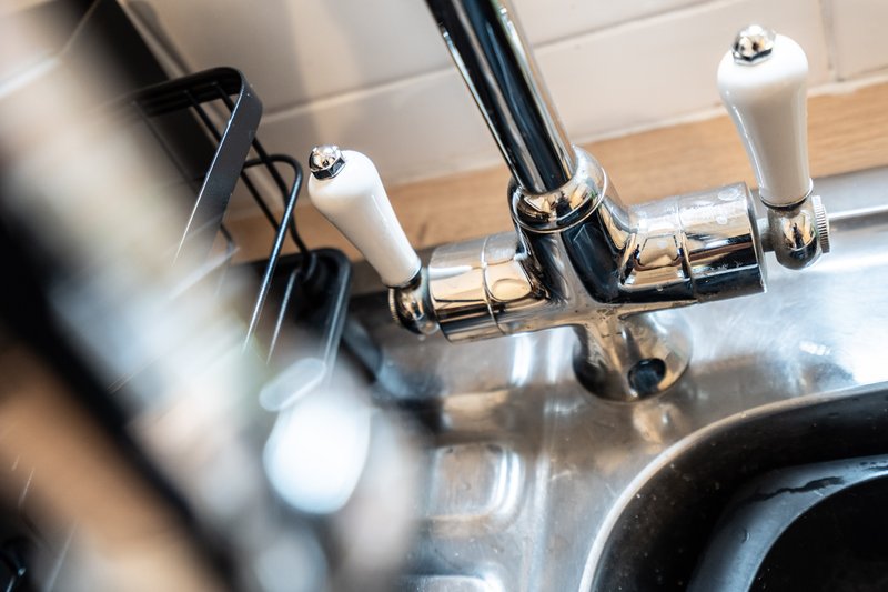 Close-up of modern kitchen sink faucet with chrome finish and white handles
