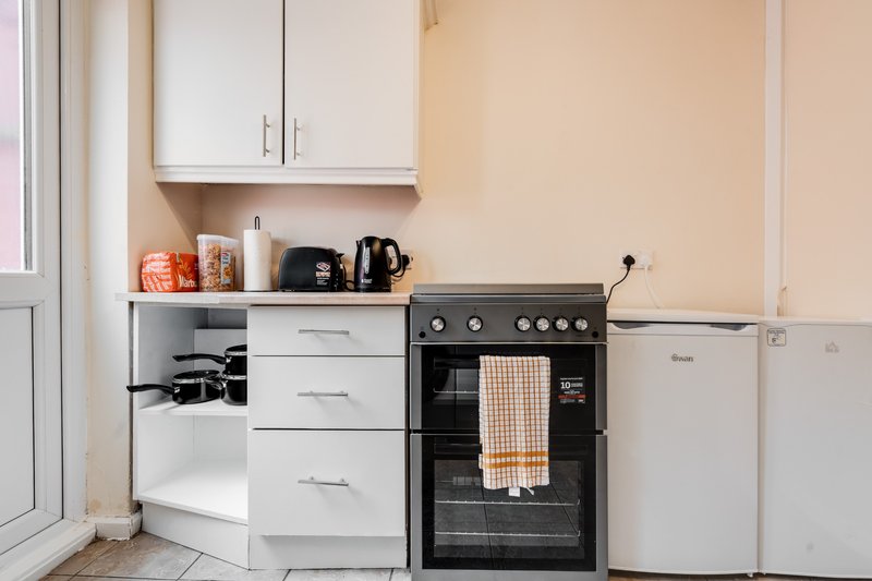 Kitchen with white cabinets, black electric oven, white fridge and countertop appliances