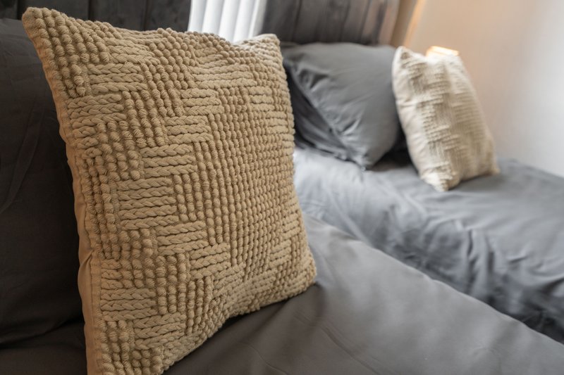 Gray upholstered sofa with textured cushions and throw pillows in neutral tones