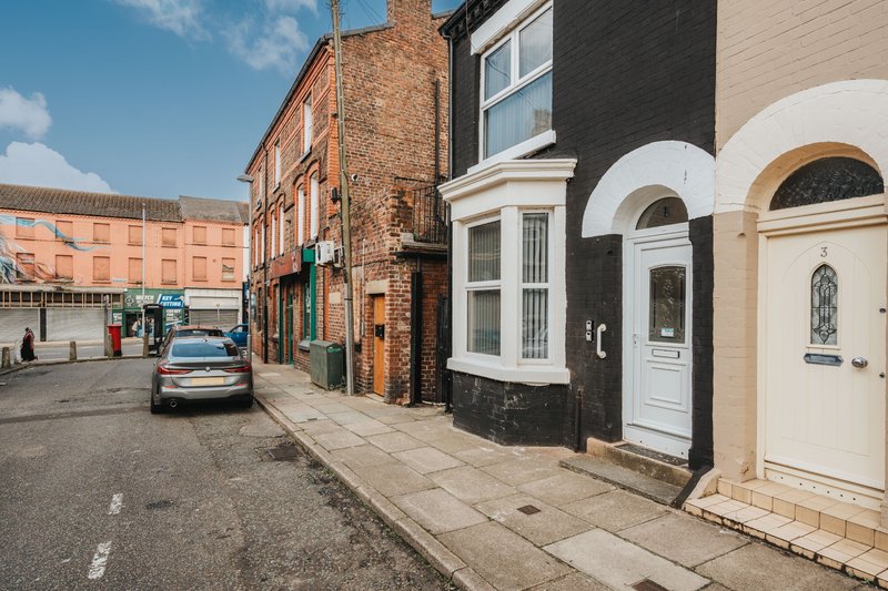 Street view of brick terraced houses with parked car and mixed architectural styles