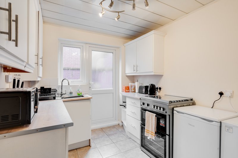Modern kitchen with white cabinets, stainless steel appliances, and patio doors