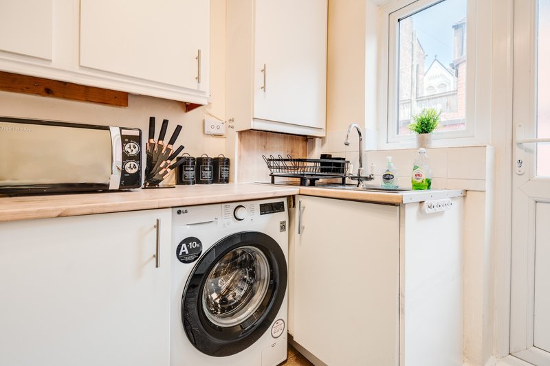 Modern kitchen with integrated washing machine, white cabinetry, and natural light from window