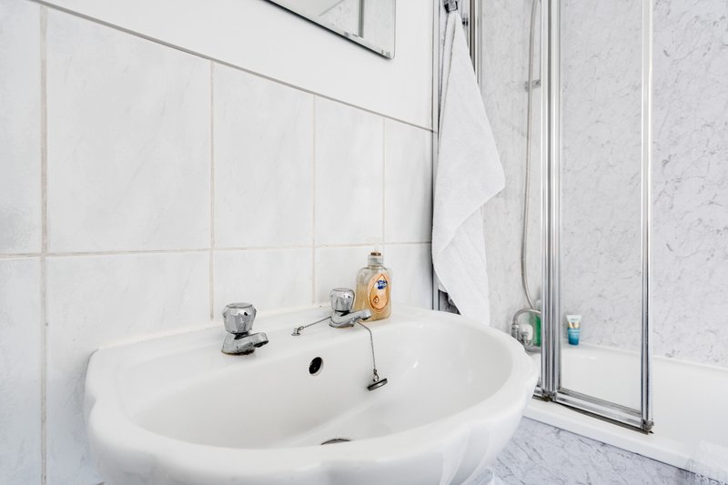 Modern bathroom with white oval sink, chrome fixtures, and shower enclosure