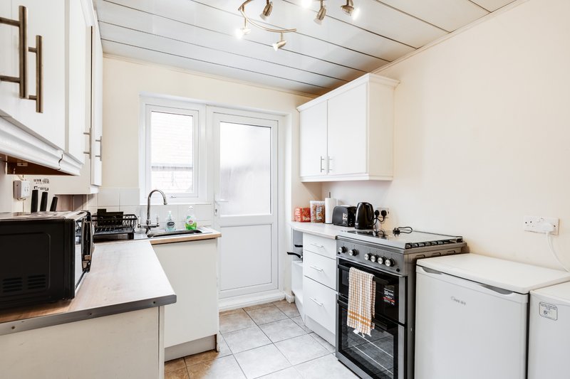 Modern kitchen with white cabinetry, stainless steel appliances, countertop workspace and glass doors