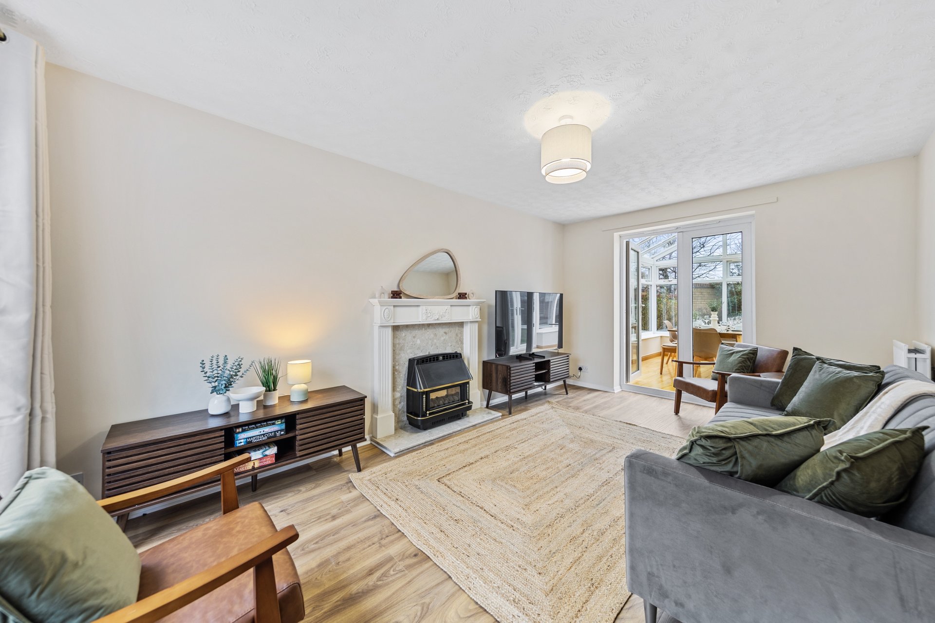 Spacious living room with fireplace, wooden flooring, grey sofa, and modern furnishings