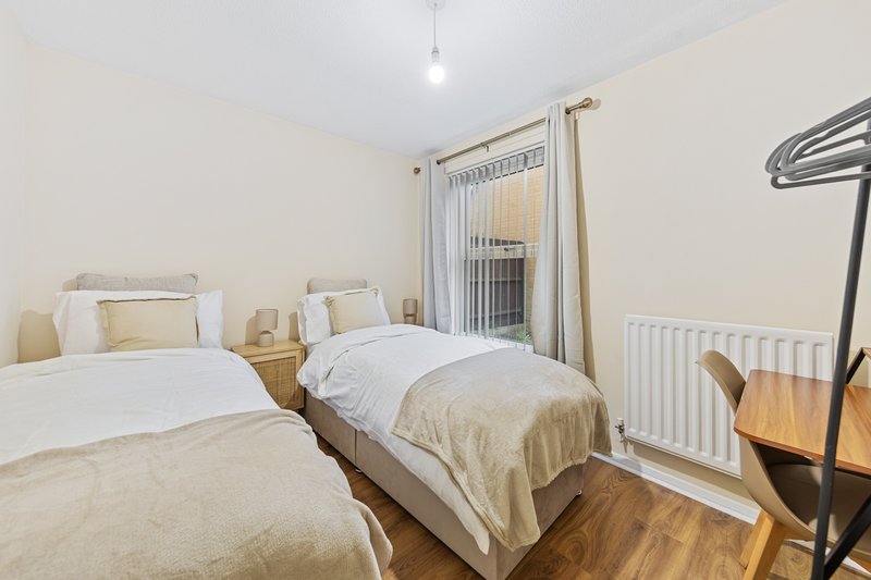 Twin bedroom with two single beds, wooden floor, and glass balcony door