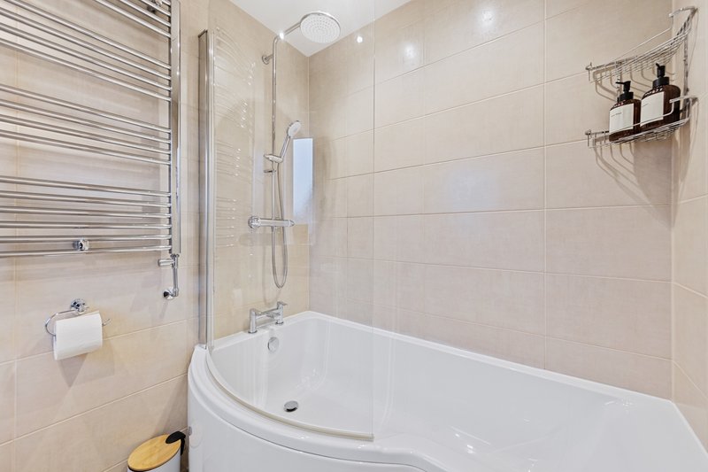 Modern bathroom with corner bathtub, glass shower screen, heated towel rail and sink