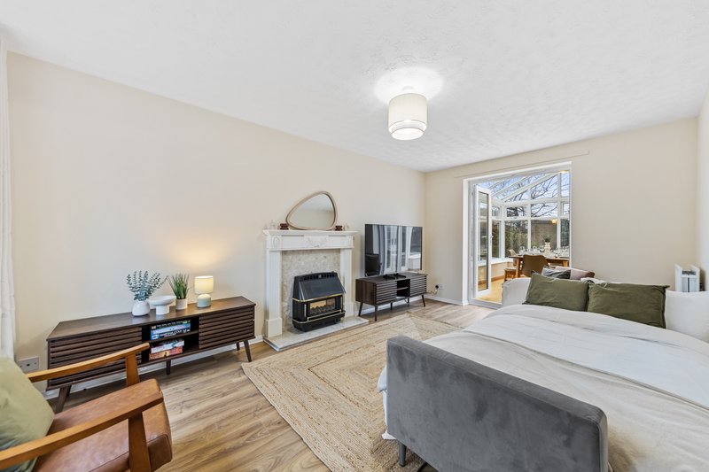 Bright bedroom with double bed, fireplace, wooden dresser and patio doors to garden