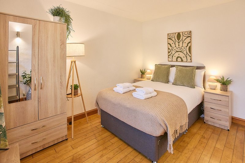 Bright bedroom with double bed, wooden wardrobe, lamp and bedside tables