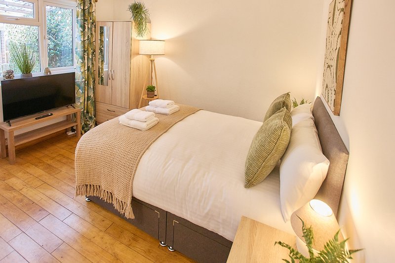 Bright bedroom with double bed, wooden floor, TV, and contemporary furnishings