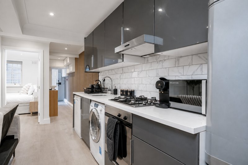 Modern kitchen with dark cabinetry, white subway tile backsplash, gas hob, and integrated washing machine