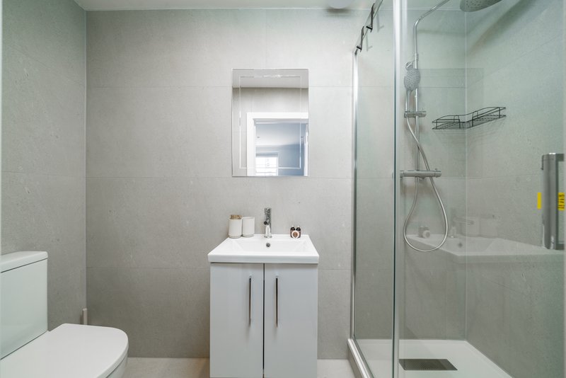 Modern bathroom with white vanity, toilet, walk-in shower enclosure and mirror