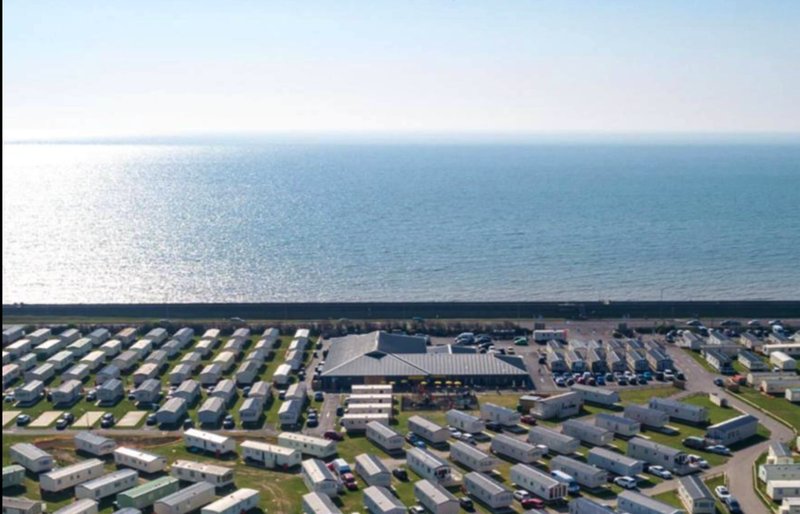 Aerial view of caravan park beside sea with rows of caravans and central buildings