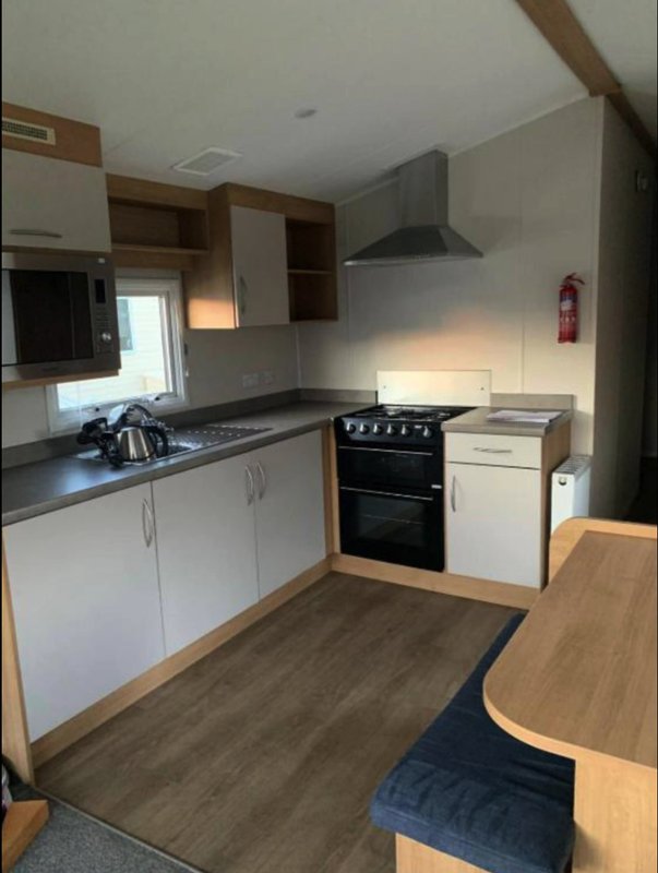 Modern kitchen with white cabinets, black range cooker, and wood dining table