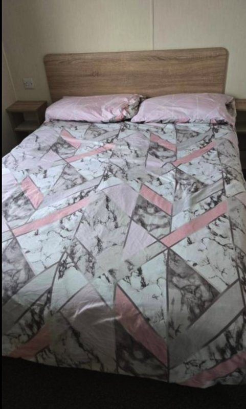 Bedroom with wooden headboard, patterned bedding in pink and white tones