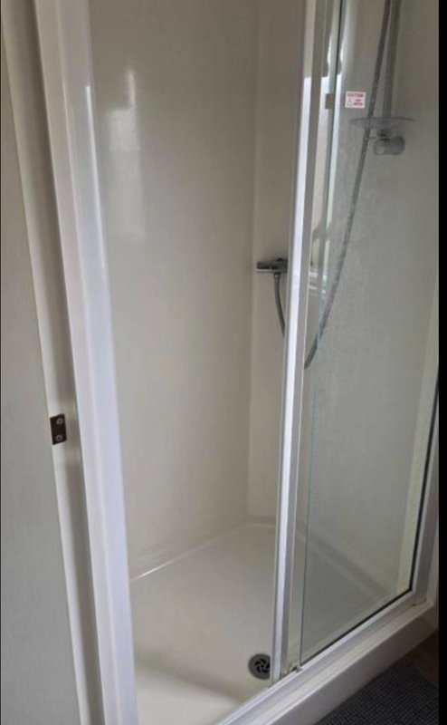 Modern shower enclosure with glass door and white walls, interior view