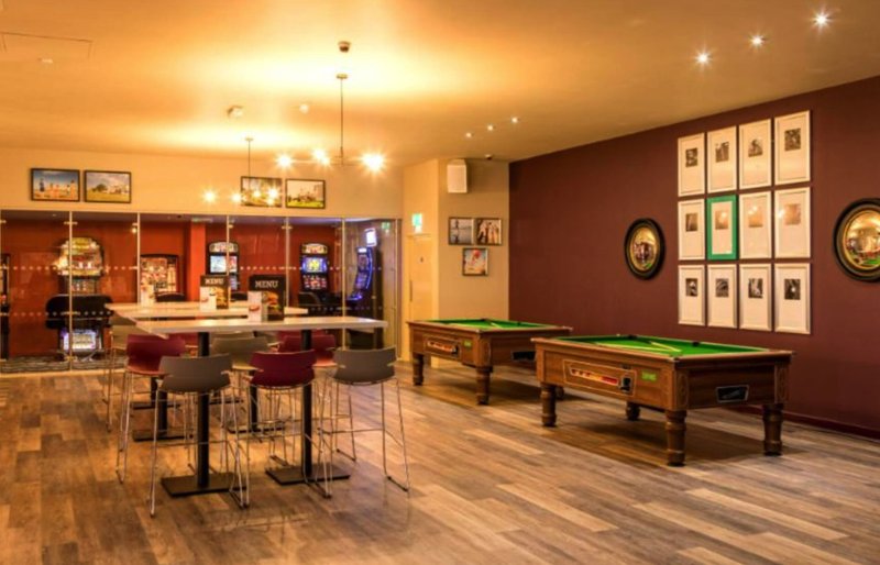 Large recreational room with pool table, bar seating, and framed wall art