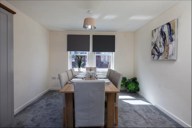 Modern dining room with wooden table, grey chairs, pendant light and window seating