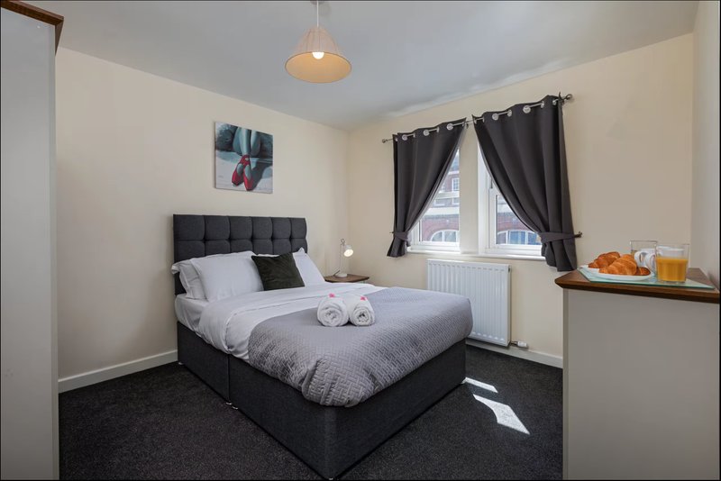 Bedroom with double bed, black headboard, pendant light, dark curtains and radiator