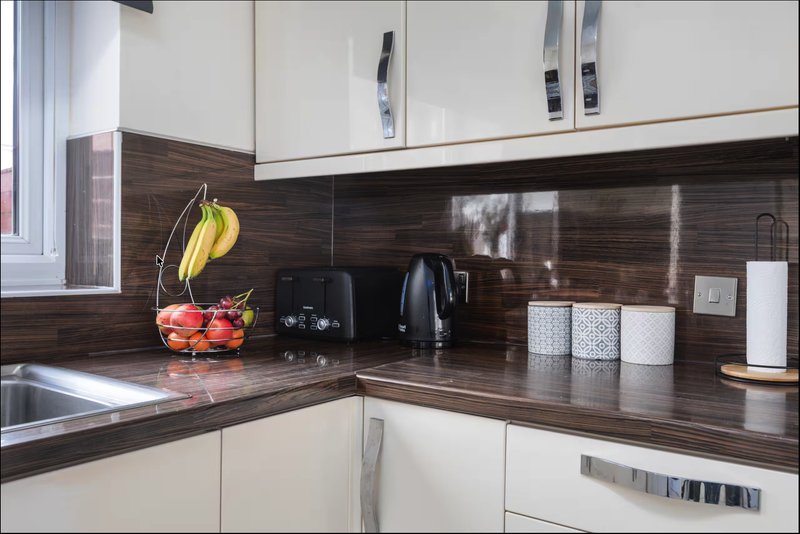 Modern kitchen with white cabinets, dark wood countertop, and stainless steel appliances