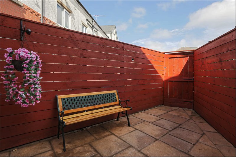 Rooftop terrace with red wooden fencing, bench seating, and flowering hanging basket