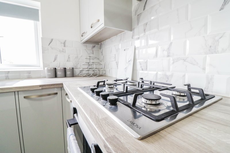 Modern kitchen with white marble backtile, gas hob, and stainless steel appliances