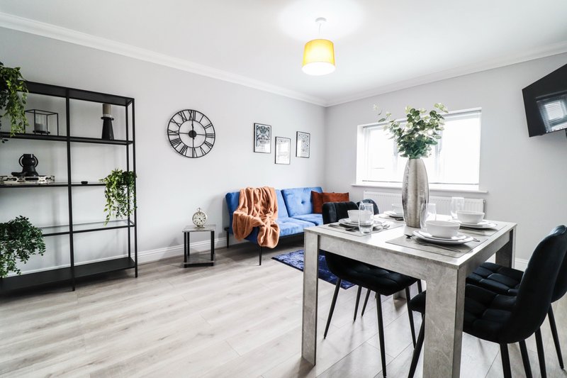 Modern open-plan living and workspace with desk, sofa, shelving unit and dining table