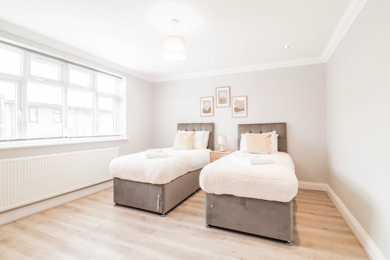 Bright twin bedroom with two single beds, wooden floor, large window and framed wall art