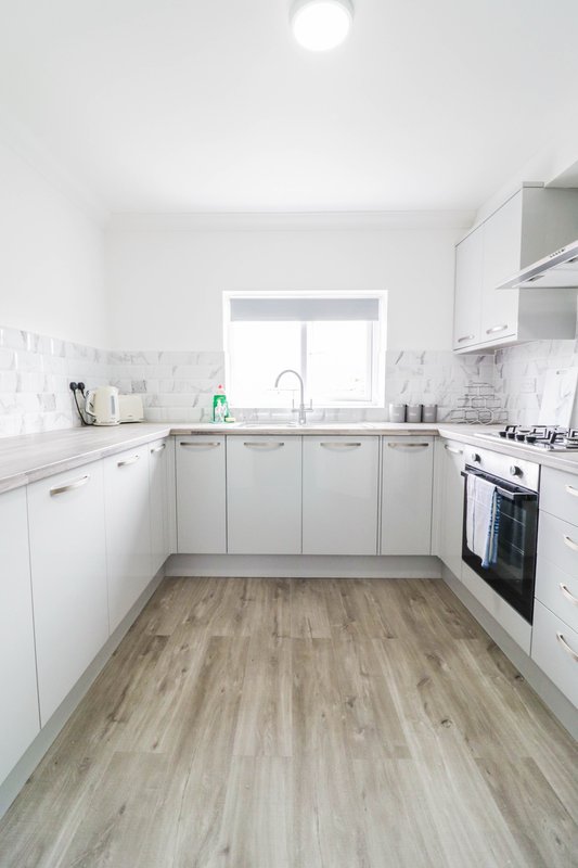 Modern white kitchen with wooden floor, gas cooker, and bright window