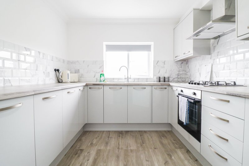 Modern white kitchen with subway tile backsplash, gas cooker, and wooden flooring