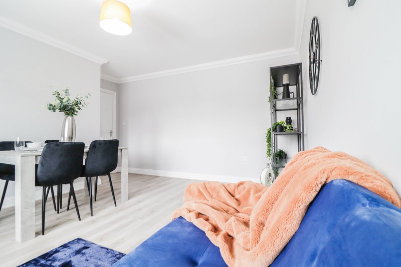 Modern bedroom with blue bedding, peach throw blanket, desk area and shelving unit