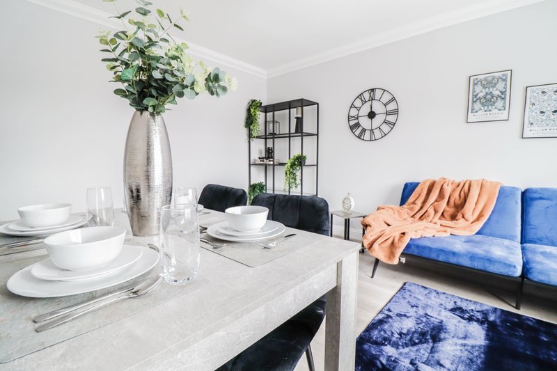 Open-plan living and dining area with white marble table, blue sofa, and potted plant