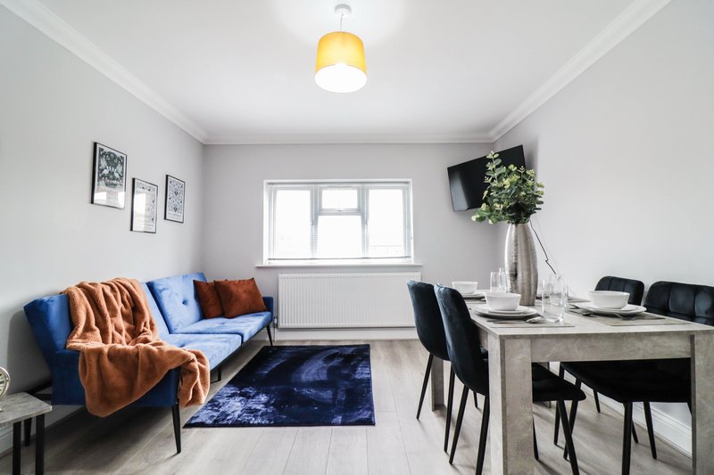Open-plan living and dining area with blue sofa, dining table, and large window