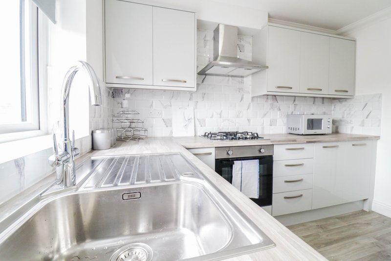 Modern white kitchen with stainless steel sink, marble backtile and gas cooktop