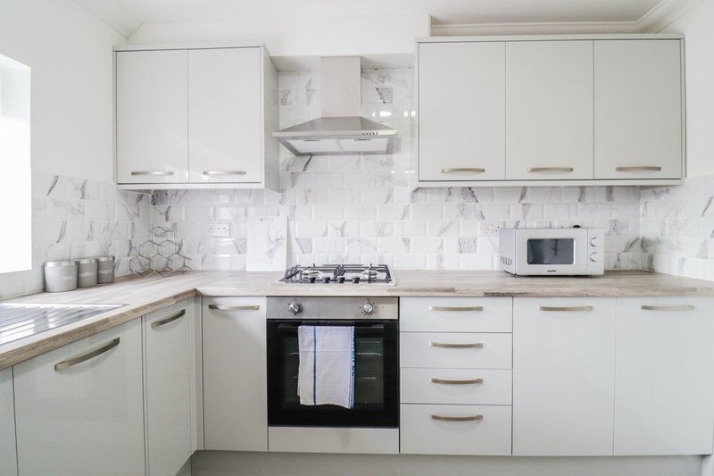 Modern kitchen with white cabinetry, marble backsplash, gas hob and black oven