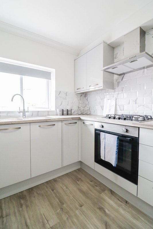 Modern kitchen with white cabinetry, marble backsplash, stainless steel appliances and window