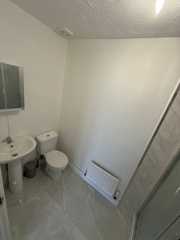 Small bathroom with toilet, sink, shower enclosure and tiled flooring
