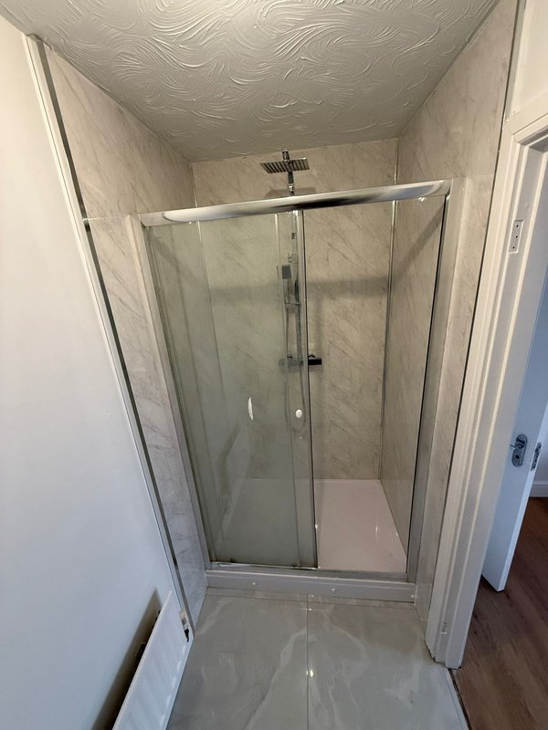Bathroom with frameless glass shower enclosure and marble tile walls