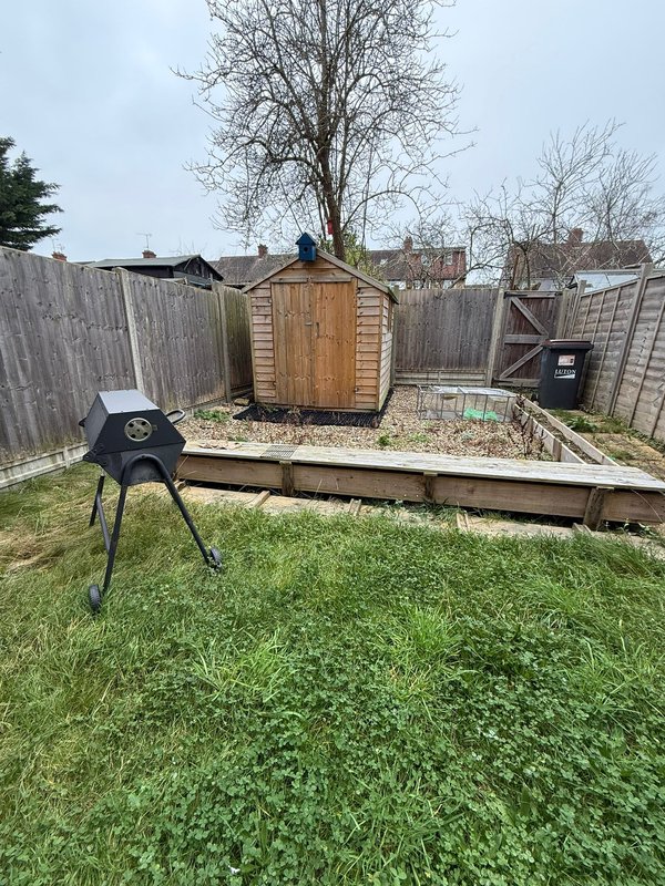 Garden with wooden shed, raised bed, black fire pit and wooden fencing