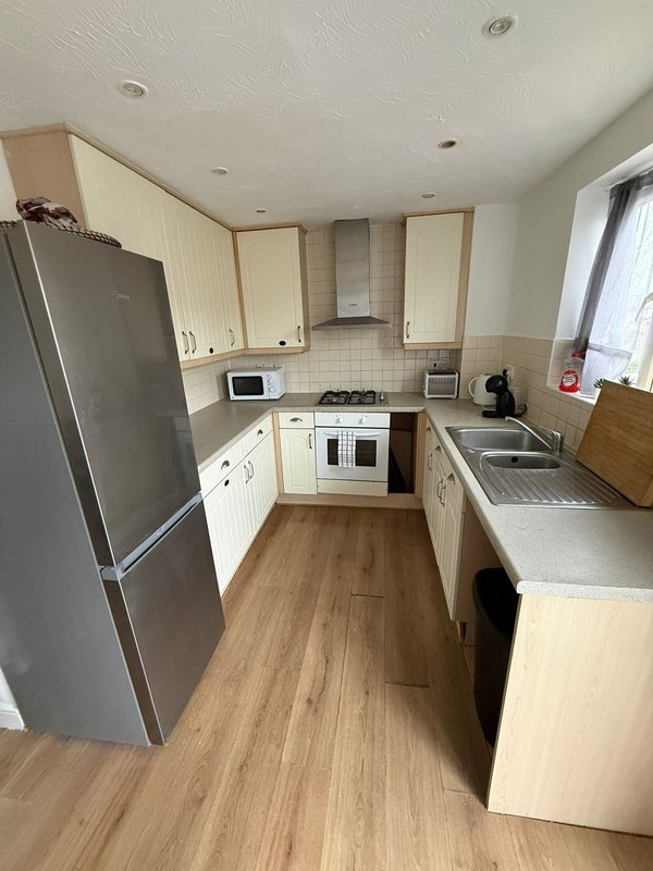 Kitchen with cream cabinets, stainless steel appliances, wooden flooring and window