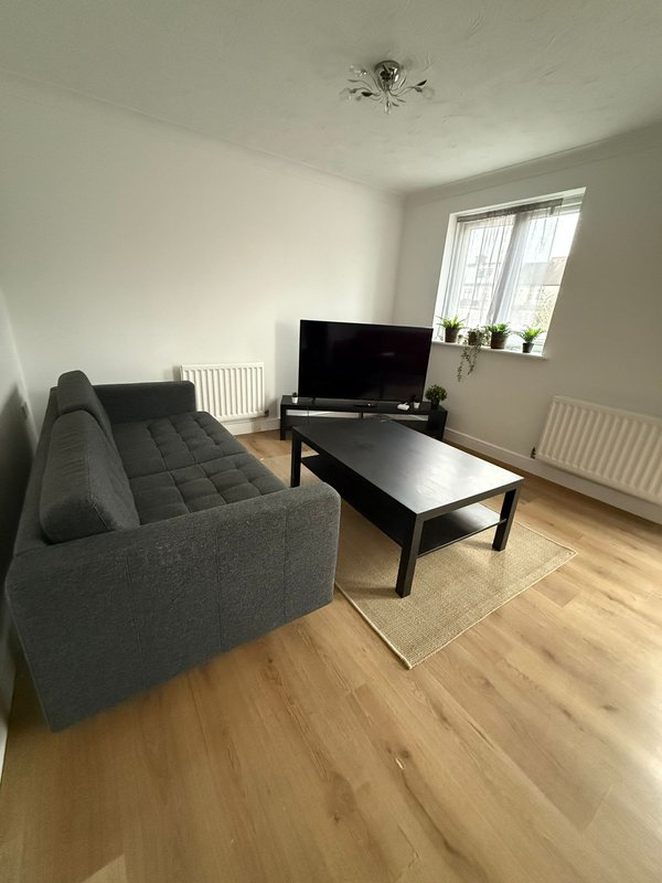 Bright living room with gray sofa, black TV stand, coffee table and wooden flooring